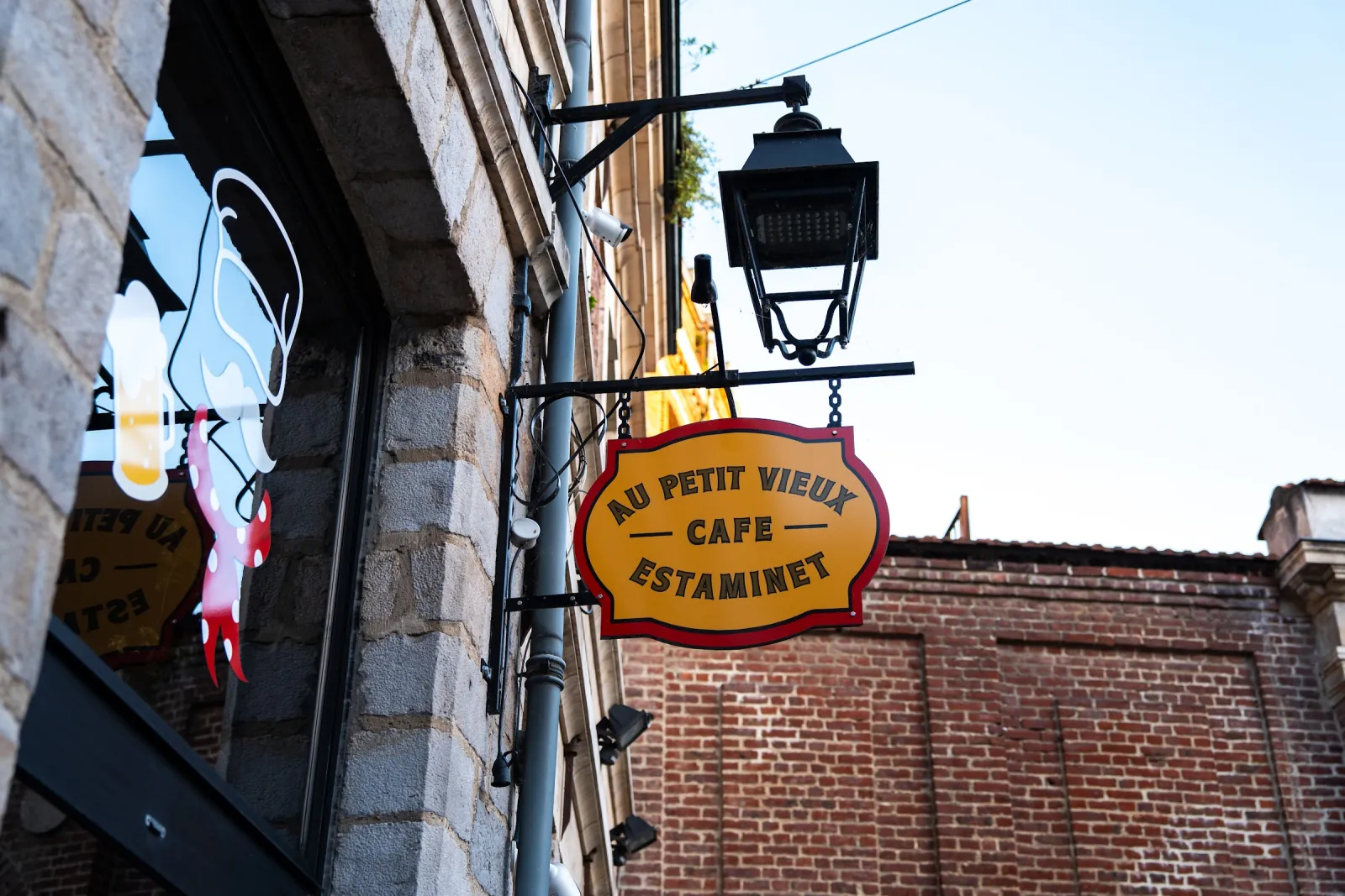 L'enseigne ronde du Petit Vieux, « café estaminet », suspendue sous une lanterne, place aux Oignons.